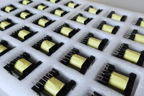 Tray of ferrite transformers with yellow-taped cores on pinned bobbins
